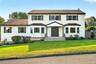 Two-story exterior featuring  vinyl siding, dark-toned shutters, a covered front entryway with double doors, symmetrical bay windows, and a shingled r