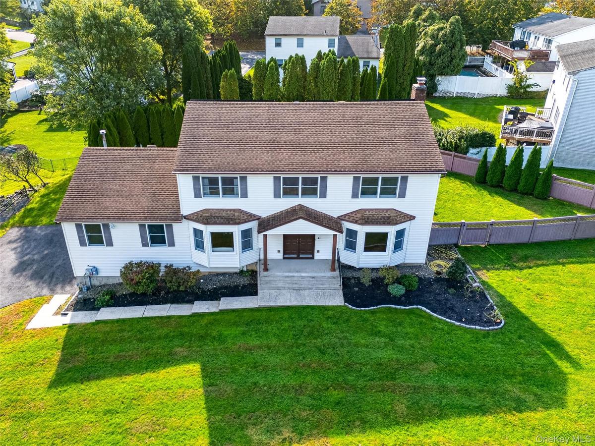 Two-story colonial residence featuring  siding, a multi-gabled roofline, dual front-facing bay windows, and a covered entryway with a  walkway