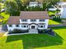 Two-story colonial residence featuring  siding, a multi-gabled roofline, dual front-facing bay windows, and a covered entryway with a  walkway