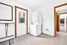 Utility space featuring a stacked washer and dryer unit, an exterior door with a glass insert, and wood-trim finishes
