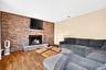 Full-height brick accent wall featuring an integrated wood-burning fireplace, raised stone hearth, and built-in wooden mantelpiece, complemented by ha