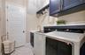 Custom laundry room featuring upgraded cabinetry, a utility sink, hanging rack and countertop above the washer and dryer.