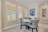 Sunlit breakfast nook surrounded by windows with plantation shutters, conveniently located beside the kitchen.