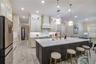 Upgraded kitchen featuring an oversized island with seating, contrasting cabinetry and designer pendant lighting.