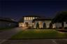 Twilight view of the paver driveway and front entrance with warm exterior lighting.