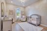 Charming bedroom featuring hardwood flooring, a decorative accent wall and chandelier lighting.