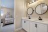 Double-sink vanity featuring white cabinetry, contrasting black fixtures and coordinating round mirrors.