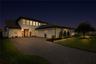 Evening exterior highlights illuminated garden beds and the landscaped front lawn.