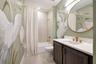 Beautifully styled bathroom featuring a bird-pattern accent wall, upgraded vanity and tub with shower.