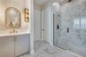 Upgraded bathroom featuring a glass-enclosed shower, floor-to-ceiling tile and a coordinating vanity with designer lighting.