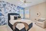 Bedroom featuring a blue statement accent wall, plush carpet and space for a reading chair.