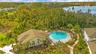 Community pool and clubhouse surrounded by landscaped grounds and mature trees.