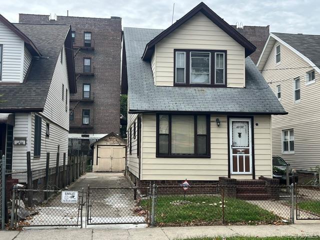 View of front of house featuring a gate, a fenced front yard, a shed, and driveway