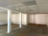 Open-concept partially finished basement space featuring white walls, drop ceiling panels, structural support columns, recessed windows, and closed of