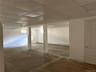 Open-concept partially finished basement space featuring white walls, drop ceiling panels, structural support columns, recessed windows, and closed of