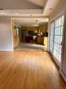 Hardwood flooring, vaulted ceilings, and glass-pane sliding patio doors leading to a kitchen with wood cabinetry and tile flooring