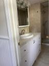Bathroom featuring white cabinetry, stone-finish countertop, integrated sink, mirrored medicine cabinet, and tiled shower enclosure