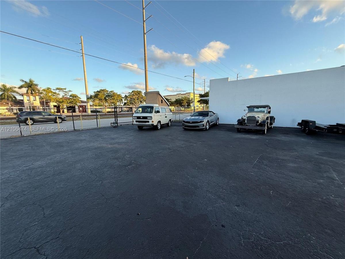 Asphalt-paved surface area with perimeter chain-link fencing and a solid masonry exterior wall