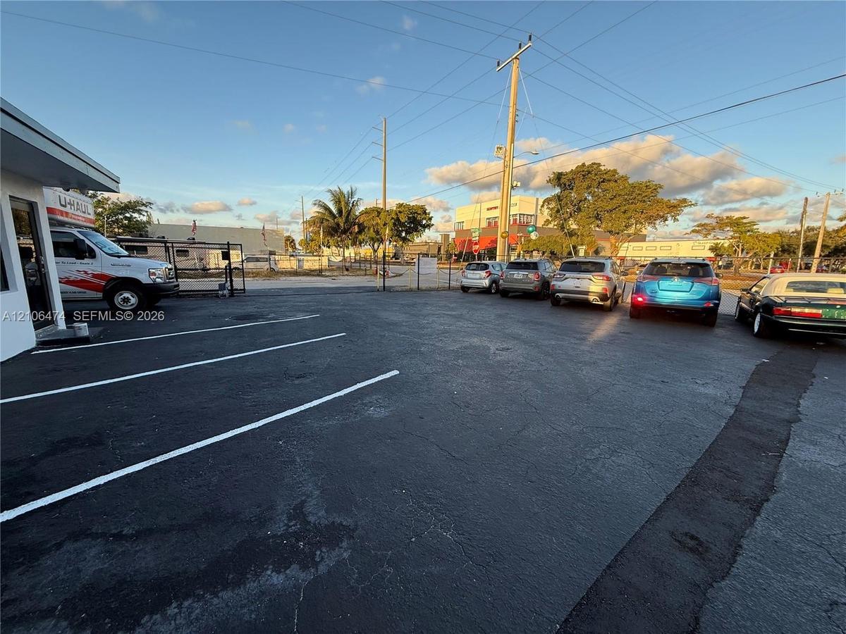 Paved asphalt parking lot featuring white-painted stall markings and a perimeter metal fence