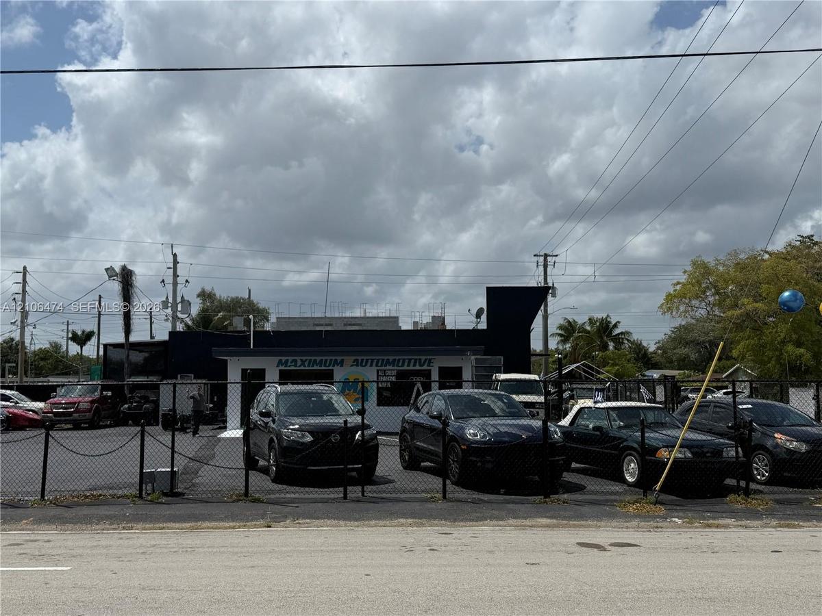 Commercial property featuring a dark-toned masonry facade, integrated signage, and a gated asphalt lot
