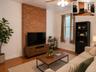 Exposed brick accent wall with wood-finish flooring, ceiling fan, and window with natural light (virtually staged)