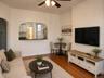 Open concept living area featuring wood-finish flooring, a ceiling fan with integrated lighting, and an arched pass-through window to the kitchen. (vi