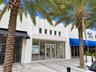 Art Deco-inspired facade featuring clean, vertical masonry detailing, extensive floor-to-ceiling glass storefront, and double-glass entry doors