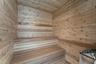 Sauna featuring wood-plank walls, multi-level built-in wooden bench seating, and an integrated heating unit