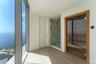 Floor-to-ceiling windows, integrated sauna with glass door and wood-finish interior, walk-in shower with stone-surround, and neutral large-format tile