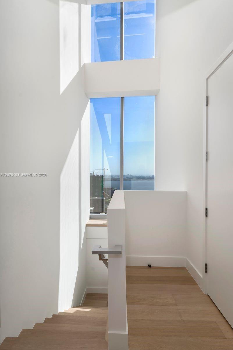 Full-height floor-to-ceiling windows, wood-finish flooring, solid-surface handrail, and minimalist interior architecture
