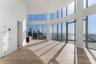 Curved floor-to-ceiling glass curtain wall, wood-finish flooring, recessed ceiling lighting, and structural cylindrical columns