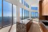 Floor-to-ceiling glass walls, kitchen island with stone countertop, wood-finish cabinetry, and wide-plank wood-finish flooring
