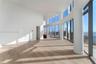 Open-concept interior featuring floor-to-ceiling curved glass windows, wood-finish flooring, recessed lighting, and structural columns