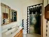 Bathroom featuring a shower with shower door, toilet, tile patterned floors, tile walls, and vanity