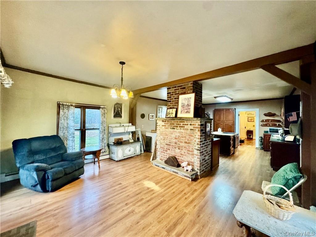 Siting room featuring light hardwood / wood-style flooring, ornamental molding, a notable chandelier, and a baseboard heating unit