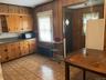 Kitchen featuring freestanding refrigerator, wood walls, dark countertops, brown cabinets, and open shelves