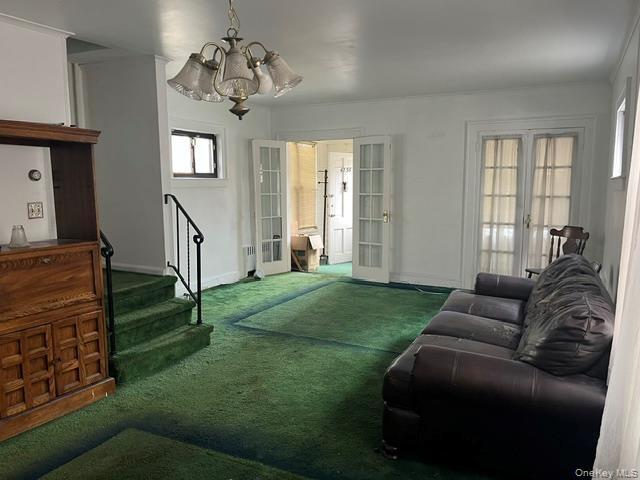 Living room featuring french doors, carpet, a chandelier, stairway, and crown molding