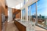 Gourmet kitchen featuring floor-to-ceiling cabinetry, stone waterfall island, integrated stainless steel appliances, and expansive double-height windo