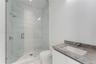 Walk-in shower with floor-to-ceiling tile, frameless glass enclosure, and stone-finish vanity countertop with integrated rectangular basin