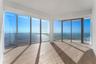 Floor-to-ceiling windows, wood-finish flooring, sliding glass door, glass-panel balcony railing, and water-fronting horizon