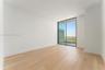 Floor-to-ceiling glass sliding door, wood-finish flooring, and white walls featuring exterior balcony access