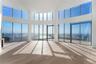 Curved wall of floor-to-ceiling windows, wood-finish flooring, recessed ceiling lighting, and structural support columns