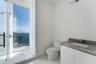 Bathroom featuring a stone-surface vanity with an integrated sink, glass-enclosed shower, polished tile flooring, and floor-to-ceiling windows