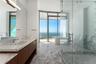 Bathroom featuring stone flooring, a wood-finish vanity with a stone countertop, a glass-enclosed walk-in shower, a freestanding soaking tub, and floo