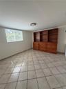 Built-in wooden cabinetry featuring open shelving and integrated drawers, ceramic tile flooring, and a window with security grating