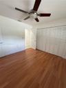 Wood-finish flooring, ceiling fan with integrated light fixture, and floor-to-ceiling louvered closet doors