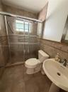 Bathroom featuring tiled walls, a glass-enclosed shower with a sliding door, pedestal sink with a metallic faucet, and tile flooring