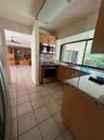 Kitchen featuring wood cabinetry, stone-finish countertops, stainless steel appliances, tile flooring, and a large window