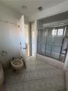 Bathroom featuring tile flooring, full-height wall tiling, a built-in floor-to-ceiling storage cabinet, and a bathtub with a sliding glass enclosure