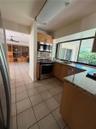 Kitchen featuring wood cabinetry, stone countertops, stainless steel appliances, ceramic tile flooring, and a large window